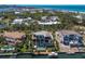 An aerial view of a luxurious waterfront home with a pool, dock, and lush landscaping, near a beautiful beach at 581 Kingfisher Ln, Longboat Key, FL 34228