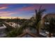 Scenic aerial view capturing the waterfront property, boat dock, lush landscaping, and vibrant sunset colors at 581 Kingfisher Ln, Longboat Key, FL 34228