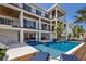 View of backyard featuring a pool, dining, outdoor kitchen, lounge chairs, and a waterfront canal under a bright blue sky at 581 Kingfisher Ln, Longboat Key, FL 34228