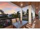 Covered balcony with a dining table, comfortable seating, and scenic views of the tranquil waterfront at sunset at 581 Kingfisher Ln, Longboat Key, FL 34228