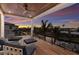 Covered balcony features wood flooring, comfortable seating, and stunning views of the waterfront and colorful sunset at 581 Kingfisher Ln, Longboat Key, FL 34228