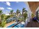 Luxury waterfront balcony with a pool, lounge chairs and canal views lined with palm trees at 581 Kingfisher Ln, Longboat Key, FL 34228