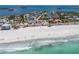 Aerial view of a sandy beach with gentle waves and a clear blue ocean, perfect for relaxation and recreation at 581 Kingfisher Ln, Longboat Key, FL 34228