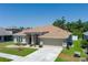 Exterior view of a tan house with a driveway, manicured lawn, a two-car garage, and stone accents at 6106 34Th E Ct, Ellenton, FL 34222