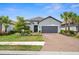 Charming single-story home featuring a gray color scheme, beautiful landscaping, and a brick driveway at 6266 Mesa Gln, Bradenton, FL 34203
