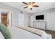 This bedroom includes wood floors, ceiling fan, TV, and view of attached bathroom at 6516 Serenity Fall Ln, Sarasota, FL 34240