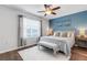Cozy bedroom boasts a ceiling fan, serene blue accent wall, and ample natural light at 6516 Serenity Fall Ln, Sarasota, FL 34240