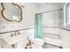 Bright bathroom featuring a pedestal sink, toilet, bathtub with shower, white tile and decorative mirror at 76 S Washington Dr, Sarasota, FL 34236