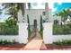 Charming two-story home with a black metal fence and gate, complemented by mature palm trees and landscaping at 76 S Washington Dr, Sarasota, FL 34236
