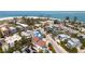 Aerial view of the coastal neighborhood showcasing a large beach home with a pool and palm trees at 803 Gladiolus St, Anna Maria, FL 34216