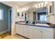 Bright bathroom featuring double sinks, dark countertops, decorative lights, mirrors and marble floors at 803 Gladiolus St, Anna Maria, FL 34216