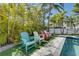 A nice poolside area features colorful Adirondack chairs, lush tropical plants, and privacy at 803 Gladiolus St, Anna Maria, FL 34216