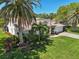 Front exterior showcasing beautiful landscaping, mature palms, and a well-maintained lawn at 8146 Shadow Pine Way, Sarasota, FL 34238