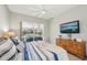 Relaxing main bedroom with TV, ceiling fan, and sliding door access to the outdoor pool area at 8146 Shadow Pine Way, Sarasota, FL 34238
