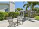An outdoor patio offers a relaxing spot with comfortable chairs, shade trees, and a view of the pool area at 8146 Shadow Pine Way, Sarasota, FL 34238