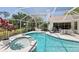 A kidney-shaped pool and attached hot tub are surrounded by a screened enclosure and lush landscaping at 8146 Shadow Pine Way, Sarasota, FL 34238