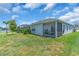Exterior view of a home showing a screened-in patio and lush green lawn in the backyard at 10616 High Noon Trl, Parrish, FL 34219