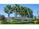 Summerwoods community entrance featuring palm trees, stone signage, and beautiful landscaping at 10616 High Noon Trl, Parrish, FL 34219