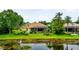Back of home featuring a screened pool, patio and lush greenery, as seen from the lake's edge at 11215 Rivers Bluff Cir, Lakewood Ranch, FL 34202