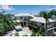 Stunning two-story home with a light-colored exterior, metal roof, balconies, and lush tropical landscaping at 1435 Westway Dr, Sarasota, FL 34236