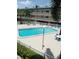 A pristine community pool surrounded by lounge chairs, palm trees and white fences at 150 Harborside Ave # 221, Punta Gorda, FL 33950