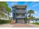 Eye-catching three-story home with dual balconies, brick-paved driveway, and palm trees at 159 Crescent Dr, Anna Maria, FL 34216