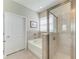 Bright bathroom featuring a soaking tub and shower combination with a glass enclosure at 17555 Cantarina Cv, Bradenton, FL 34211