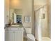 Well-lit bathroom featuring a granite vanity, framed mirror, white cabinets, and a shower behind a white curtain at 17555 Cantarina Cv, Bradenton, FL 34211