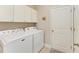 Clean laundry room featuring a washer and dryer, white cabinets and a door to an exterior space at 17555 Cantarina Cv, Bradenton, FL 34211