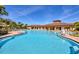 A large community pool with a clubhouse and lounge chairs under a clear blue sky at 17555 Cantarina Cv, Bradenton, FL 34211