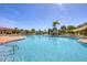 Large community swimming pool with sunshades, chairs and tables, lush landscaping and pool deck at 17555 Cantarina Cv, Bradenton, FL 34211