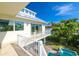 Balcony view features sleek railings overlooking the pool, complemented by lush greenery and clear blue skies at 205 17Th N St, Bradenton Beach, FL 34217
