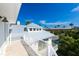 Bright balcony view features white railing, modern roofline, and neighborhood palm trees against a blue sky backdrop at 205 17Th N St, Bradenton Beach, FL 34217