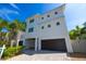 Modern two story home with brick driveway, dark garage doors, and mature tropical landscaping at 205 17Th N St, Bradenton Beach, FL 34217