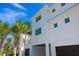 Exterior view of a multi-story home featuring a two-car garage and a well-maintained, palm-lined yard at 205 17Th N St, Bradenton Beach, FL 34217
