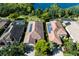 Aerial view of three homes with tile roofs, solar panels, screened pools, and lush landscaping near a lake at 2397 Vaccaro Dr, Sarasota, FL 34231