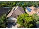 Aerial view showcases a residential home with a tile roof and solar panels, surrounded by lush landscaping and a lake nearby at 2397 Vaccaro Dr, Sarasota, FL 34231
