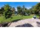 Serene backyard featuring a brick patio, lush lawn, and direct views of the lake beyond the manicured greenery at 2397 Vaccaro Dr, Sarasota, FL 34231