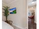 Cozy bedroom detail showing a TV, plant, and a glimpse into the living room with a comfortable red chair at 2397 Vaccaro Dr, Sarasota, FL 34231