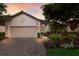 Home boasts manicured landscaping, a brick walkway, and an attached two-car garage, set against a beautiful sky at 2397 Vaccaro Dr, Sarasota, FL 34231