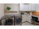 Functional laundry room featuring modern washer and dryer, built-in cabinets, and a granite countertop at 2397 Vaccaro Dr, Sarasota, FL 34231