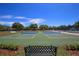 Outdoor tennis courts with blue and green surfaces, surrounded by trees and landscaping at 3816 Little Country Rd, Parrish, FL 34219