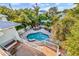 An aerial view of a backyard pool with tropical landscaping, a grill, and surrounding foliage at 426 Magnolia Ave, Anna Maria, FL 34216