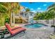 Beautiful backyard with a sparkling pool, lounge chairs, and lush tropical landscaping at 426 Magnolia Ave, Anna Maria, FL 34216