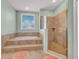 Bright bathroom featuring a soaking tub with tile surround and a glass enclosed walk-in shower at 426 Magnolia Ave, Anna Maria, FL 34216