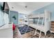 This is a bedroom with wood floors and light blue walls, featuring white bunk beds, a window, and a television at 426 Magnolia Ave, Anna Maria, FL 34216
