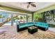 An inviting covered patio with a turquoise sectional, glass coffee table, and brick flooring at 426 Magnolia Ave, Anna Maria, FL 34216