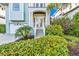 Inviting home entrance featuring double doors, a staircase, and vibrant landscaping with colorful foliage at 426 Magnolia Ave, Anna Maria, FL 34216