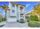 Charming two-story coastal home with a light blue exterior, lush landscaping, and a two-car garage at 426 Magnolia Ave, Anna Maria, FL 34216