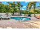 Private backyard pool surrounded by lush landscaping, lounge chairs, and outdoor grilling area at 426 Magnolia Ave, Anna Maria, FL 34216
